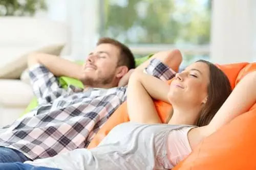 couple-resting Couple or roommates relaxing lying on comfortable poufs in the living room at home.