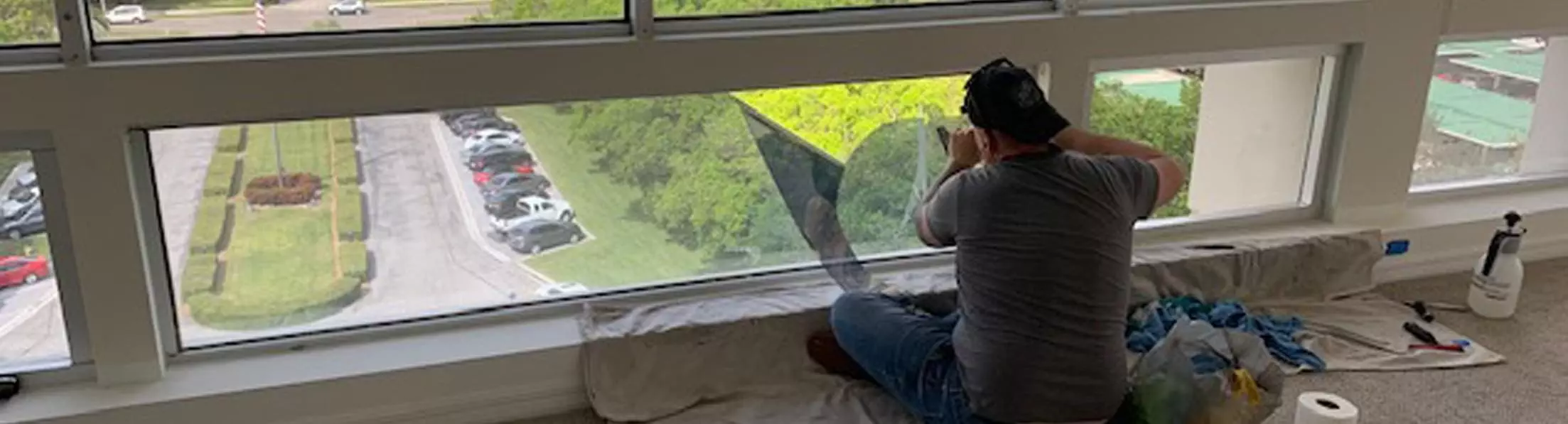 badwindow Man sitting on carpet installing window film.