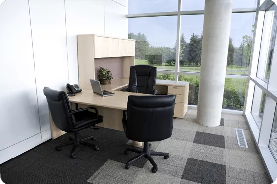 commercial-simulator office desk with three black chairs in front of windows