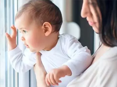 safetycallout Baby looking out a window while being held by mother.