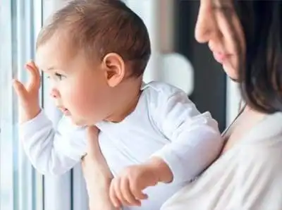 safetycallout Baby looking out a window while being held by mother.